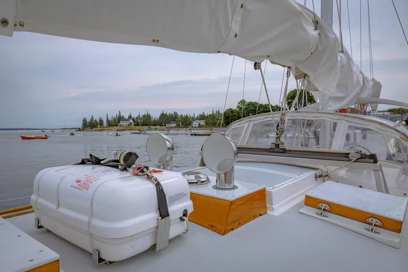 Slide: The Image of Sailboat deck view with lifeboat, Shannon 47/52 model, 2001, near a scenic shoreline. - 25