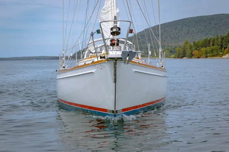 Slide: The Image of Front view of a 2001 Shannon 47/52 sailboat on calm waters near a forested shoreline. - 13