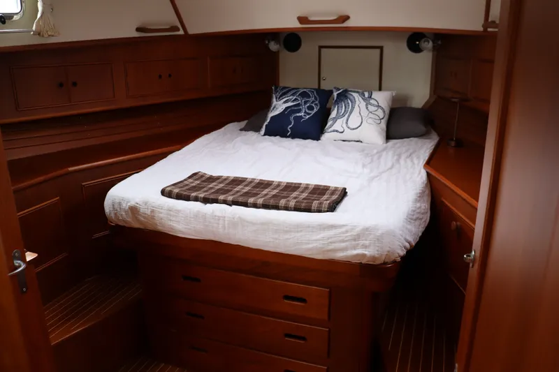Slide: The Image of Cozy cabin interior of 1996 Eastbay 40 Express Grand Banks with wooden furnishings and comfortable bedding. - 26