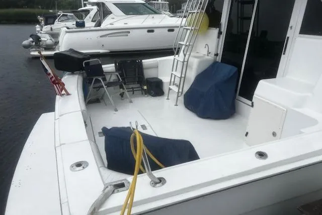 Slide: The Image of 1996 Silverton 41 Convertible yacht deck with seating and ladder, docked near other boats. - 3