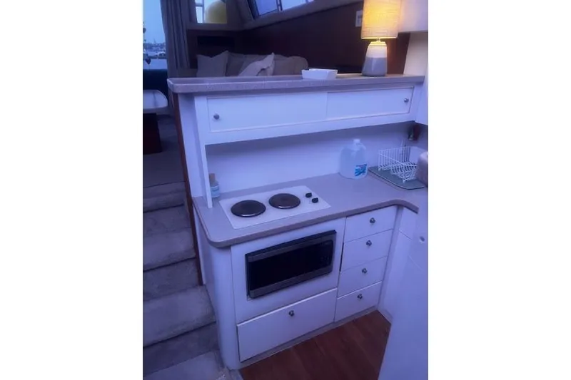 Slide: The Image of Compact kitchen area in a 1996 Silverton 41 Convertible yacht, featuring stove and microwave. - 16
