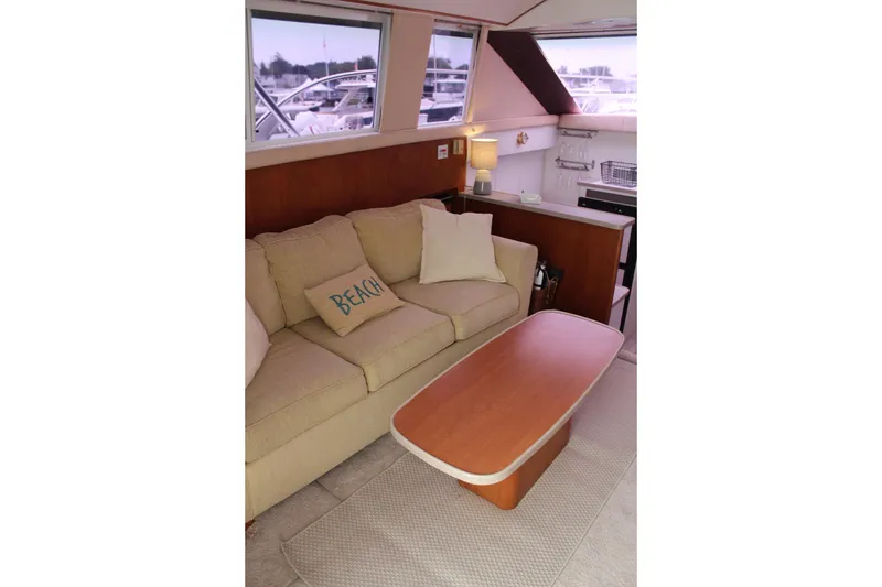 Slide: The Image of Interior of 1996 Silverton 41 Convertible yacht with beige sofa and wooden table. - 42