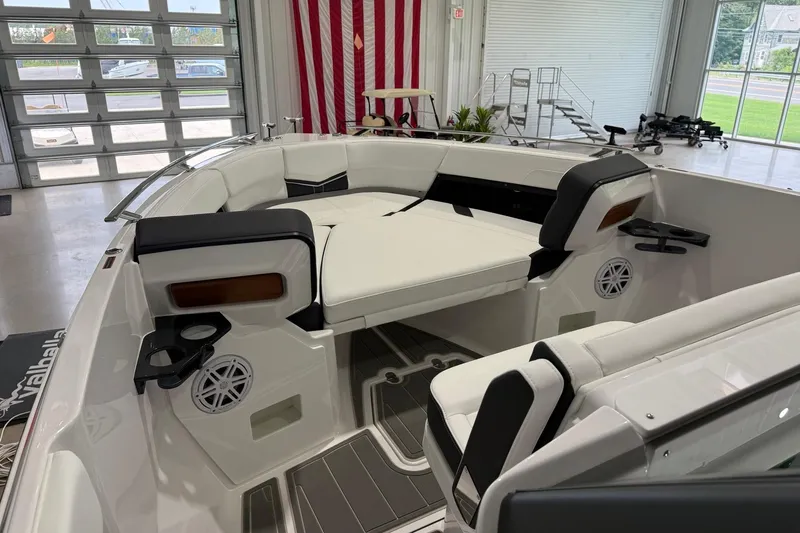 Slide: The Image of 2027 Monterey Elite 27 OB boat interior with white seating and cup holders in a showroom. - 3