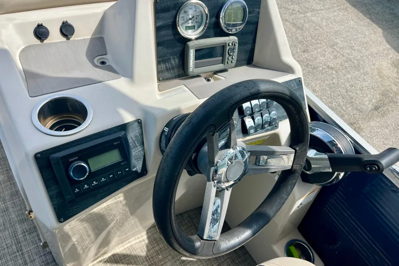 Slide: The Image of 2023 Harris Cruiser 230 boat dashboard with steering wheel and control panel. - 11