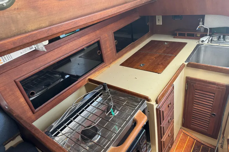 Slide: The Image of 1976 Islander 36 yacht interior kitchen with stove, sink, and wooden cabinetry. - 2