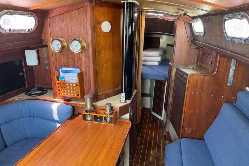 Slide: The Image of Interior of a 1976 Islander 36 sailboat with wood paneling and blue seating. - 3