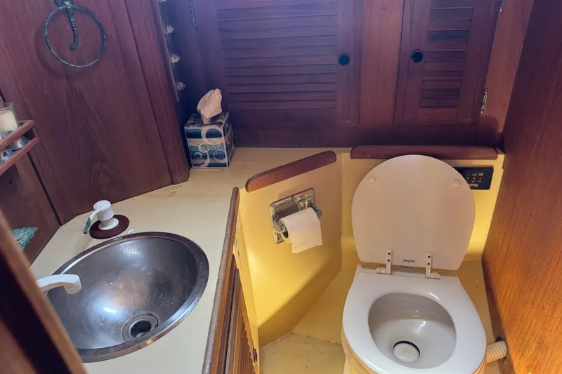 Slide: The Image of 1976 Islander 36 yacht bathroom with sink, toilet, and wooden cabinetry. - 4