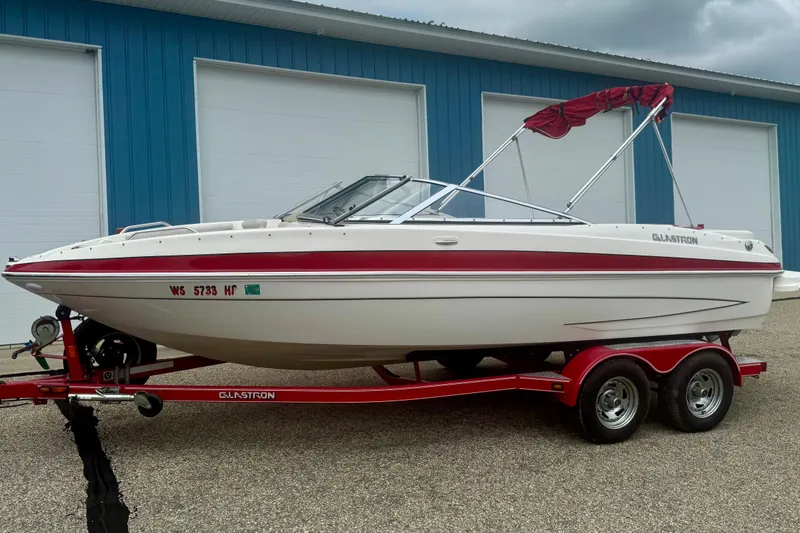 Slide: The Image of 2008 Glastron GT 225 boat on trailer, white with red accents, parked near blue building. - 3