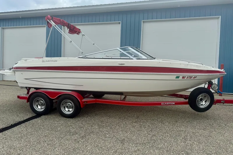 Slide: The Image of 2008 Glastron GT 225 boat on red trailer, parked outside blue garage. - 4
