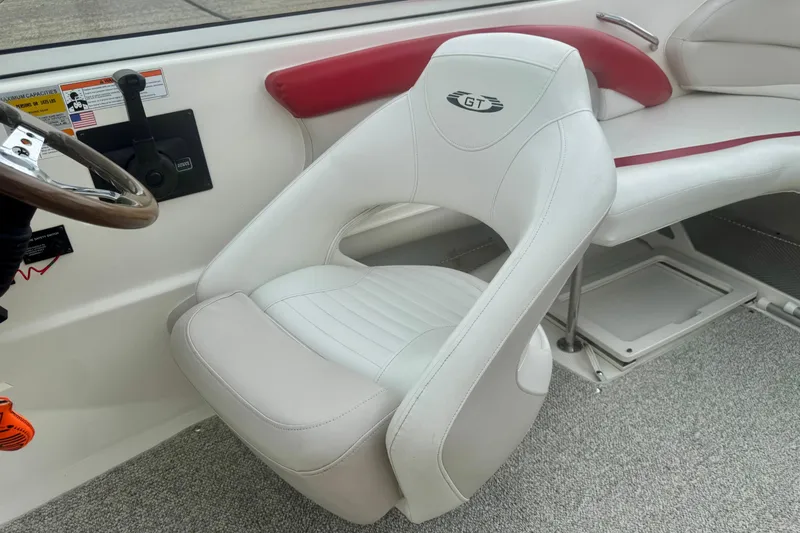 Slide: The Image of 2008 Glastron GT 225 boat interior with white and red seating, steering wheel, and carpeted floor. - 28