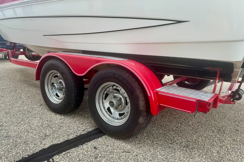 Slide: The Image of 2008 Glastron GT 225 boat on a red trailer, parked on asphalt. - 12