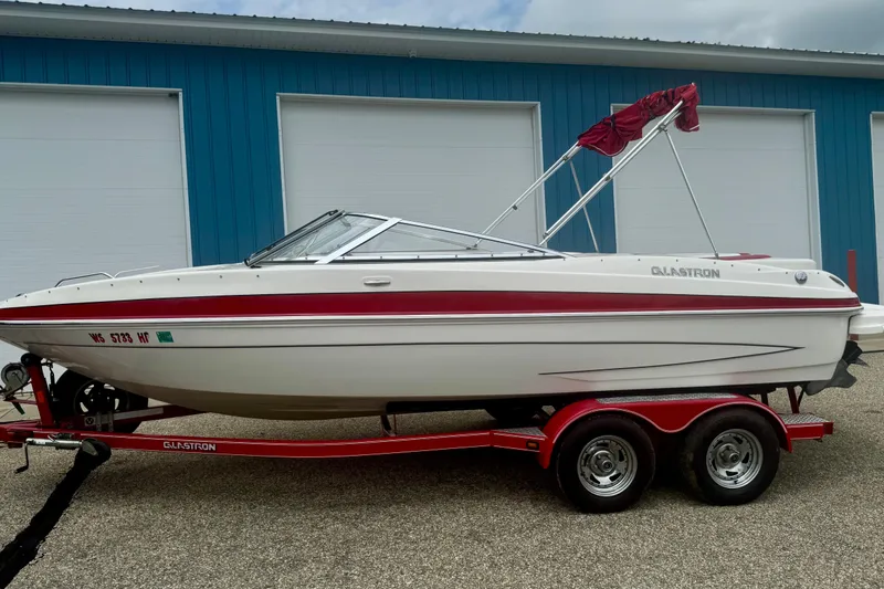 Slide: The Image of 2008 Glastron GT 225 boat on red trailer, parked outside blue building. - 68