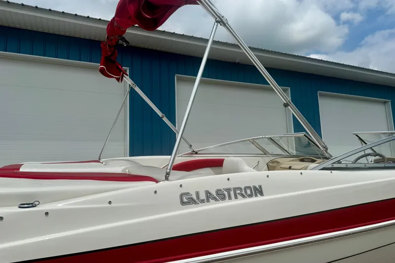 Slide: The Image of 2008 Glastron GT 225 boat with red and white design, parked near a blue building. - 65