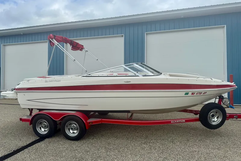 Slide: The Image of 2008 Glastron GT 225 boat on red trailer, parked outside blue building. - 6