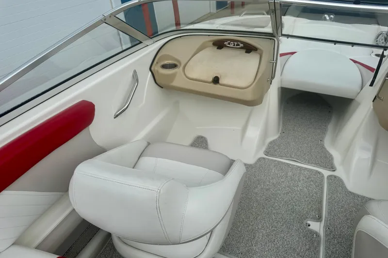 Slide: The Image of 2008 Glastron GT 225 boat interior with white and red seating, gray carpet, and dashboard. - 35