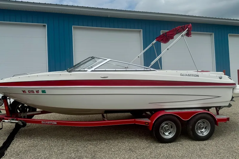 Slide: The Image of 2008 Glastron GT 225 boat on red trailer, parked near blue building. - 5