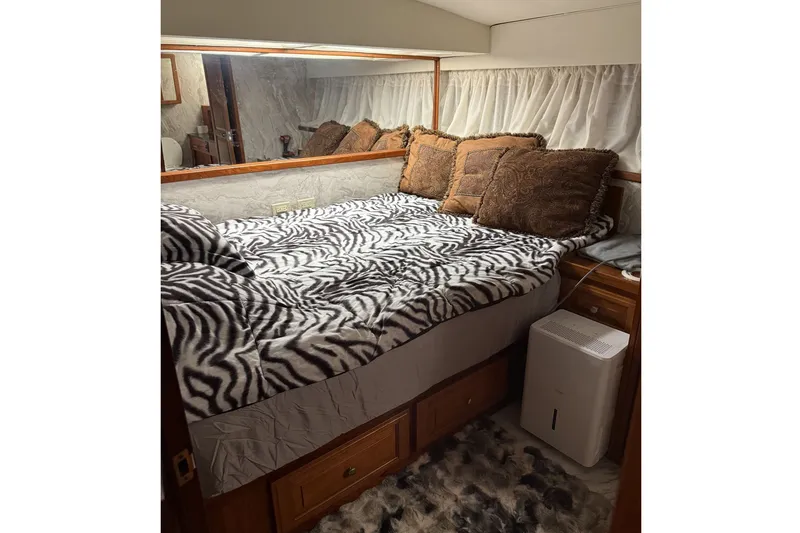 Slide: The Image of The image shows a cozy cabin with a bed covered in zebra-patterned bedding. There are pillows and a dehumidifier. - 14