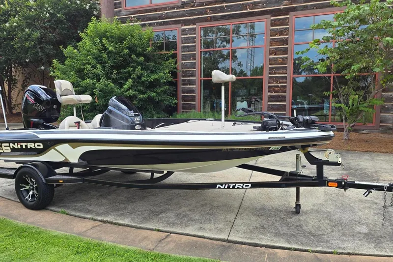 Slide: The Image of 2013 Nitro Z-6 boat on trailer, parked outside rustic building with greenery. - 6