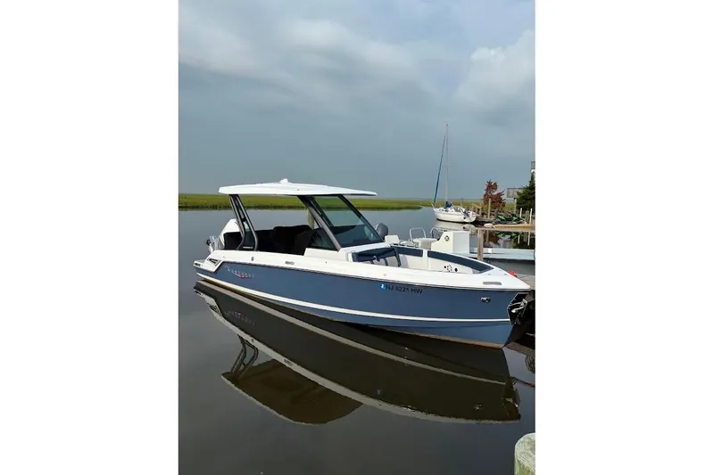 The Image of 2026 Monterey Elite 25 OB boat docked on calm water. - 0