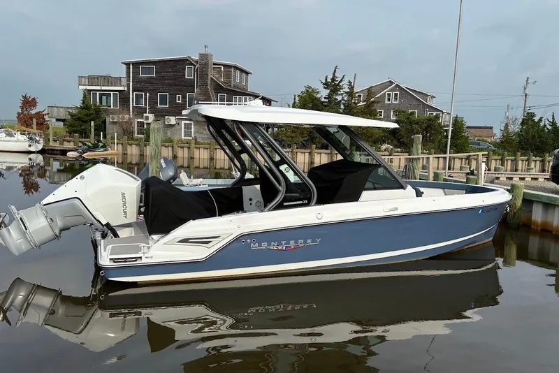 Slide: The Image of 2026 Monterey Elite 25 OB boat docked in a serene marina setting. - 1