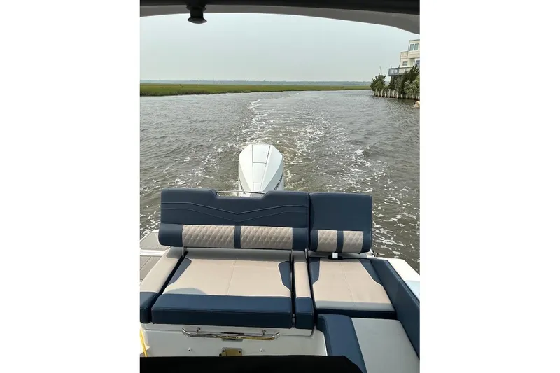 Slide: The Image of 2026 Monterey Elite 25 OB cruising on a serene waterway, featuring luxurious seating. - 7