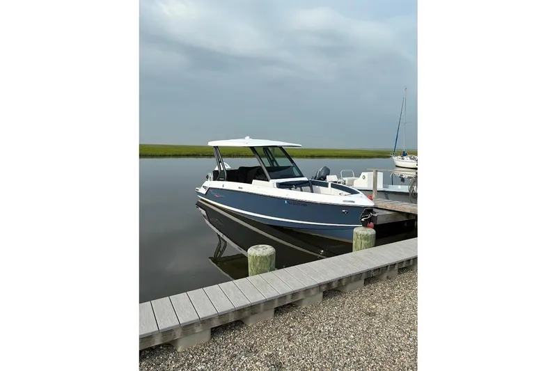 Slide: The Image of 2026 Monterey Elite 25 OB boat docked on calm water under cloudy sky. - 3