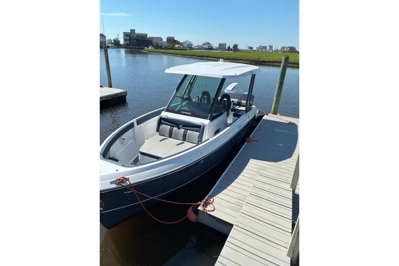 The Image of 2026 Monterey Elite 25 OB boat docked by a serene waterfront. - 1