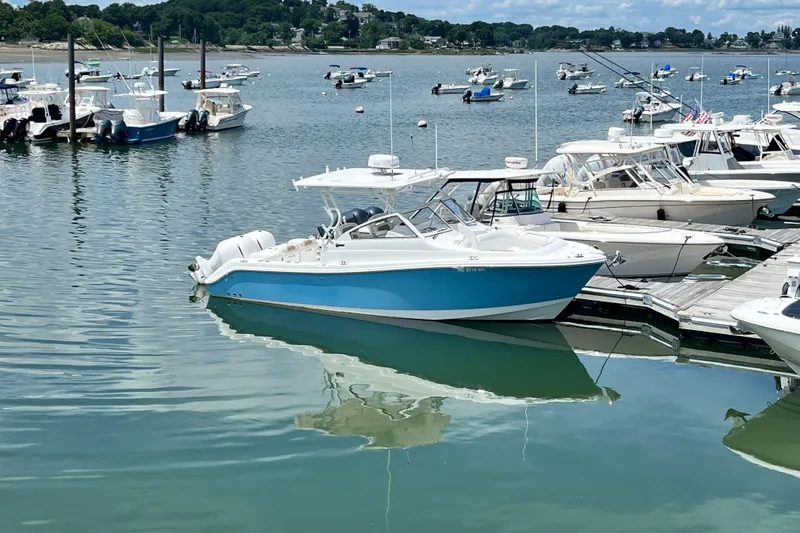 Slide: The Image of 2014 Edgewater 280CX Crossover boat docked in a marina, surrounded by other vessels. - 2