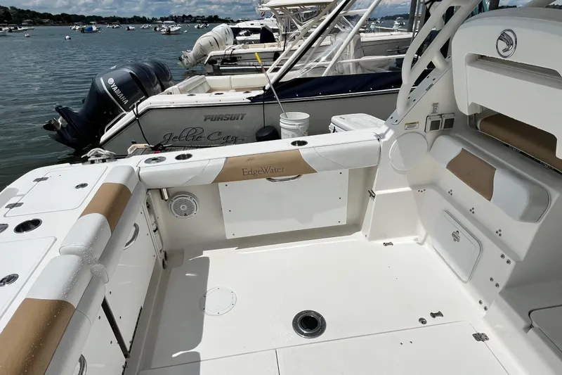 Slide: The Image of 2014 Edgewater 280CX Crossover boat interior, featuring spacious seating and storage, docked by the water. - 12