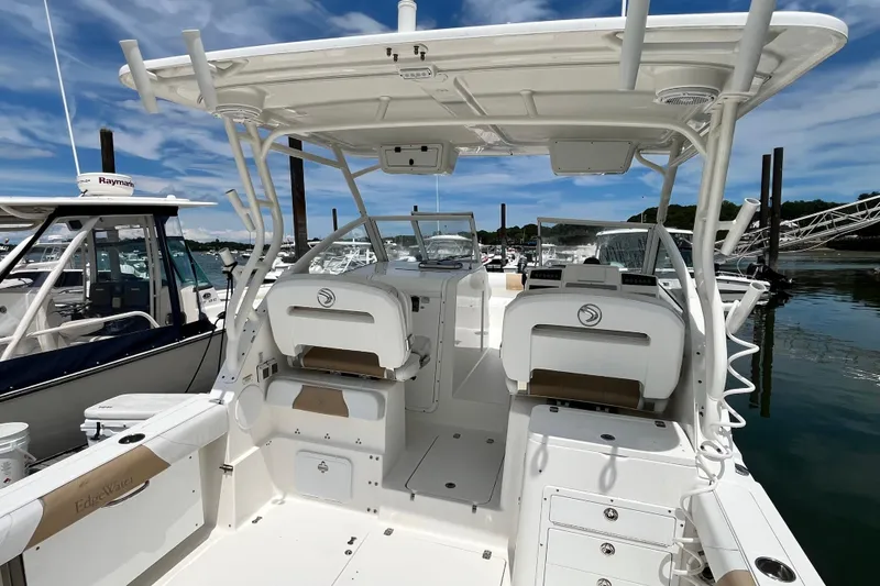 Slide: The Image of 2014 Edgewater 280CX Crossover boat interior at marina, showcasing seating and helm. - 17