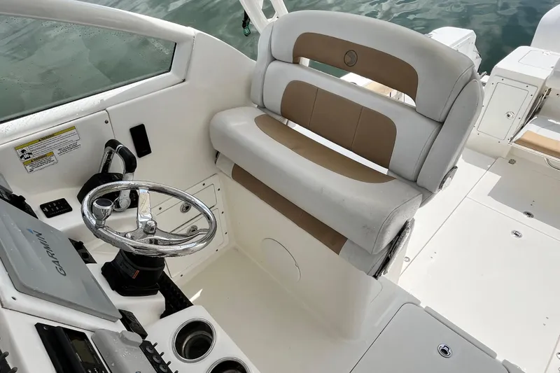 Slide: The Image of 2014 Edgewater 280CX Crossover boat helm with steering wheel and cushioned seating. - 21
