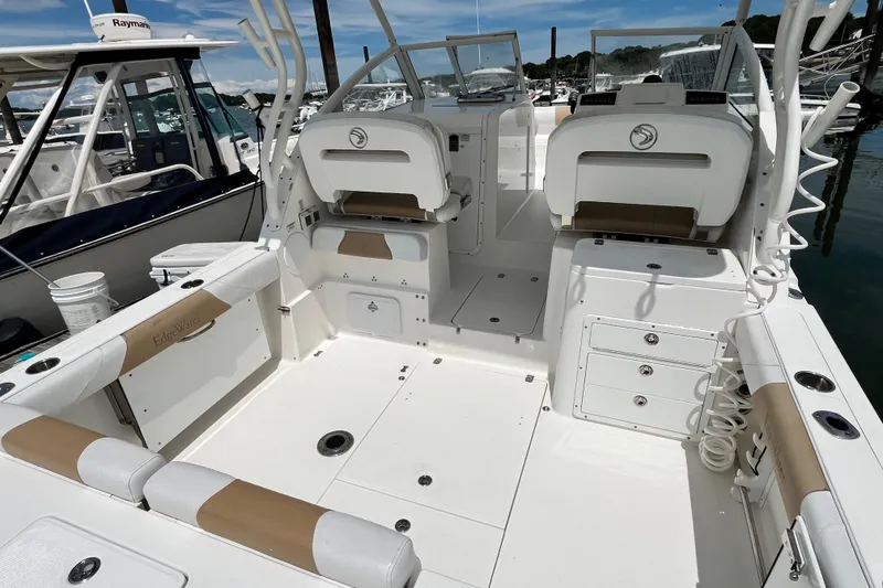 Slide: The Image of 2014 Edgewater 280CX Crossover boat interior with seating and storage, docked at marina. - 11