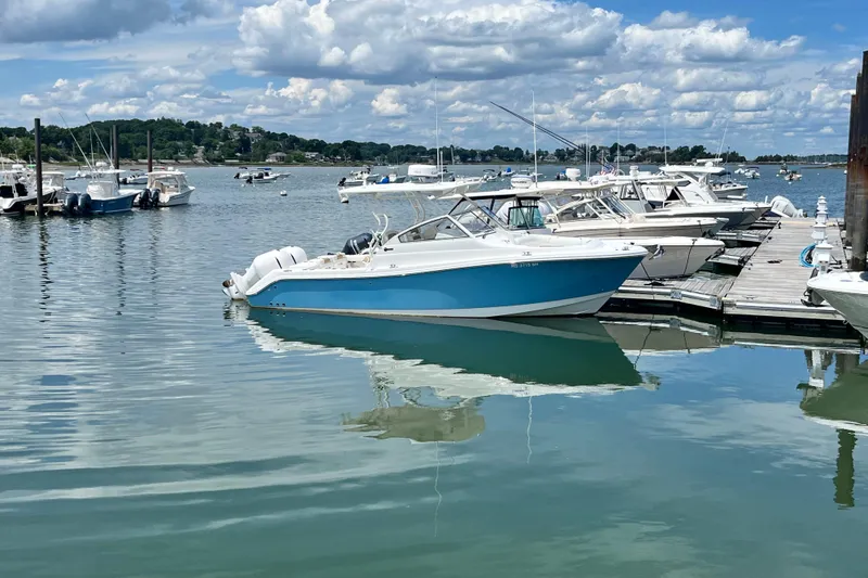The Image of 2014 Edgewater 280CX Crossover boat docked in a scenic marina under a cloudy sky. - 0
