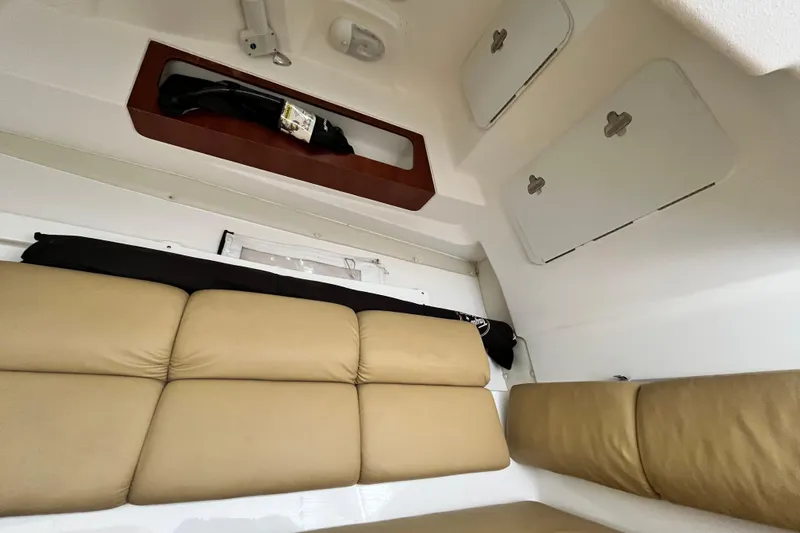 Slide: The Image of Interior of a 2014 Edgewater 280CX Crossover boat with beige seating and storage compartments. - 32