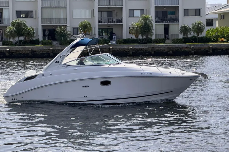 Slide: The Image of 2009 Sea Ray 270 Sundancer boat cruising on a calm waterway near residential buildings. - 5
