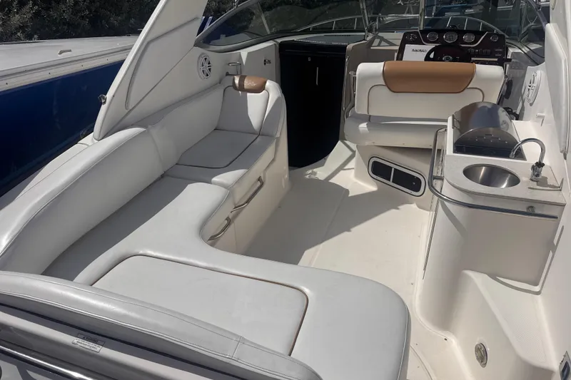 Slide: The Image of 2009 Sea Ray 270 Sundancer interior with white seating, helm, and compact kitchenette. - 12