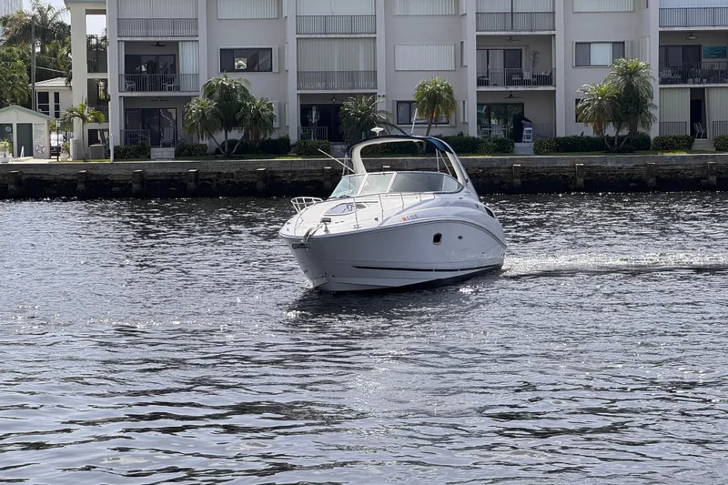 Slide: The Image of 2009 Sea Ray 270 Sundancer cruising on a calm waterway near waterfront apartments. - 3