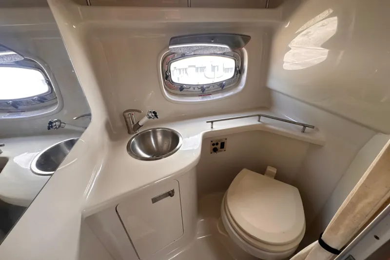 Slide: The Image of 2009 Sea Ray 270 Sundancer bathroom with sink, toilet, and porthole window. - 22