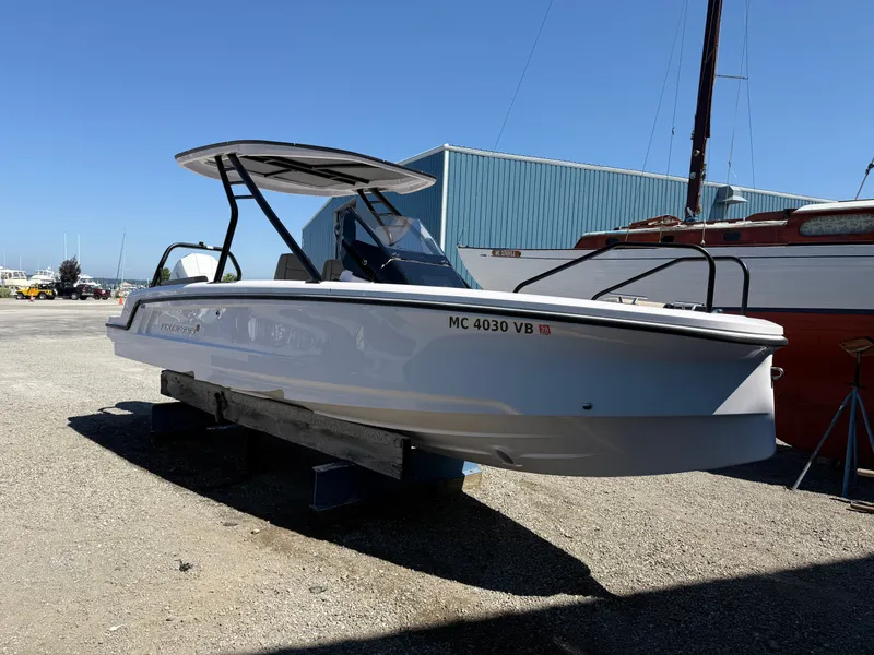 Slide: The Image of A 2024 Axopar 22 T-Top boat is on a stand in a harbor area. - 2