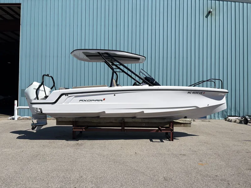 Slide: The Image of A 2024 Axopar 22 T-Top boat on a trailer in front of a blue building. - 11