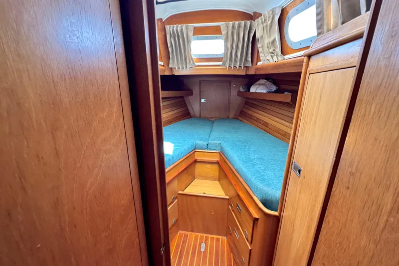 Slide: The Image of Interior of a 1970 Hincley 38 sailboat with wooden cabinetry and blue cushions. - 31