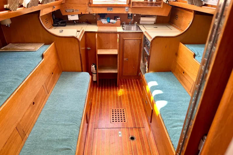 Slide: The Image of Interior of a 1970 Hincley 38 sailboat with wooden furnishings and blue cushions. - 23