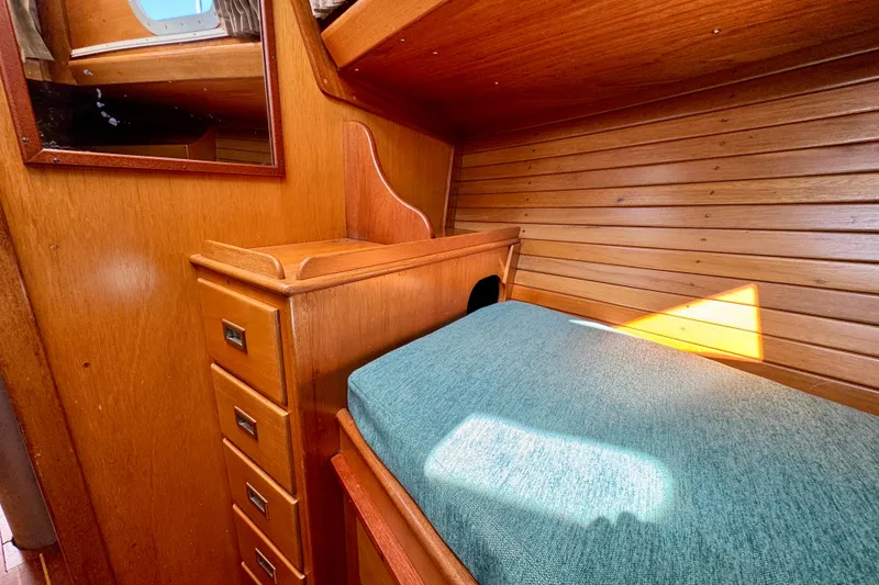 Slide: The Image of Cozy wooden cabin interior of a 1970 Hincley 38 boat with teal bedding. - 33