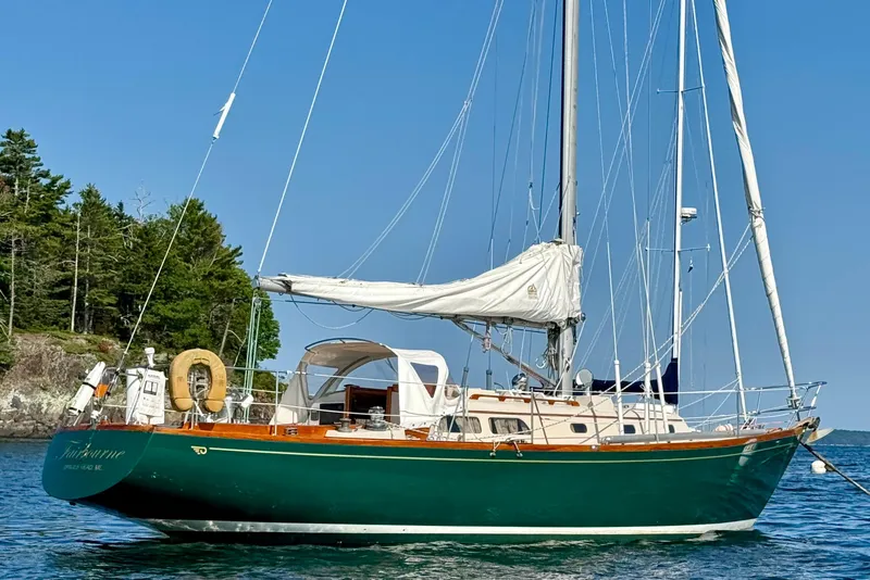 Slide: The Image of Classic 1970 Hincley 38 sailboat with green hull, anchored near forested shoreline. - 37