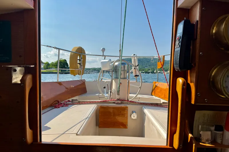 Slide: The Image of Interior view of a 1970 Hincley 38 sailboat cockpit with scenic water backdrop. - 19
