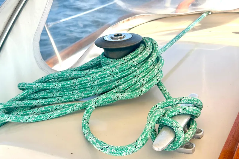 Slide: The Image of Green rope coiled on a 1970 Hincley 38 sailboat deck, near a cleat and winch. - 16