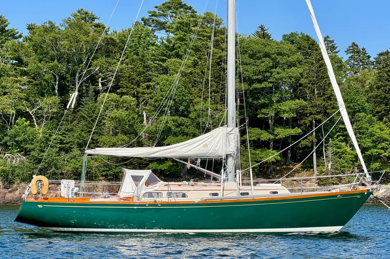 Slide: The Image of Vintage 1970 Hincley 38 sailboat with green hull, anchored near lush forest shoreline. - 5