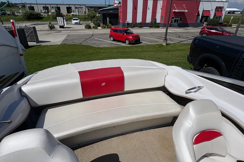 Slide: The Image of 2011 Four Winns H190SS boat interior with red and white seating, parked near a building. - 4