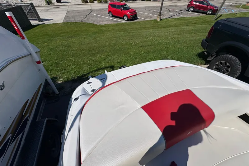 Slide: The Image of 2011 Four Winns H190SS boat interior with red and white seating, parked near grass. - 7