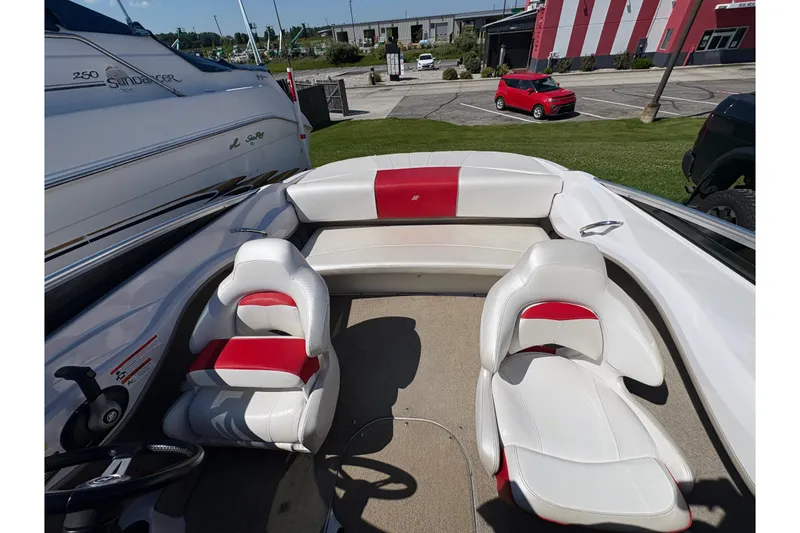 Slide: The Image of 2011 Four Winns H190SS boat interior with white and red seating, docked outdoors. - 3